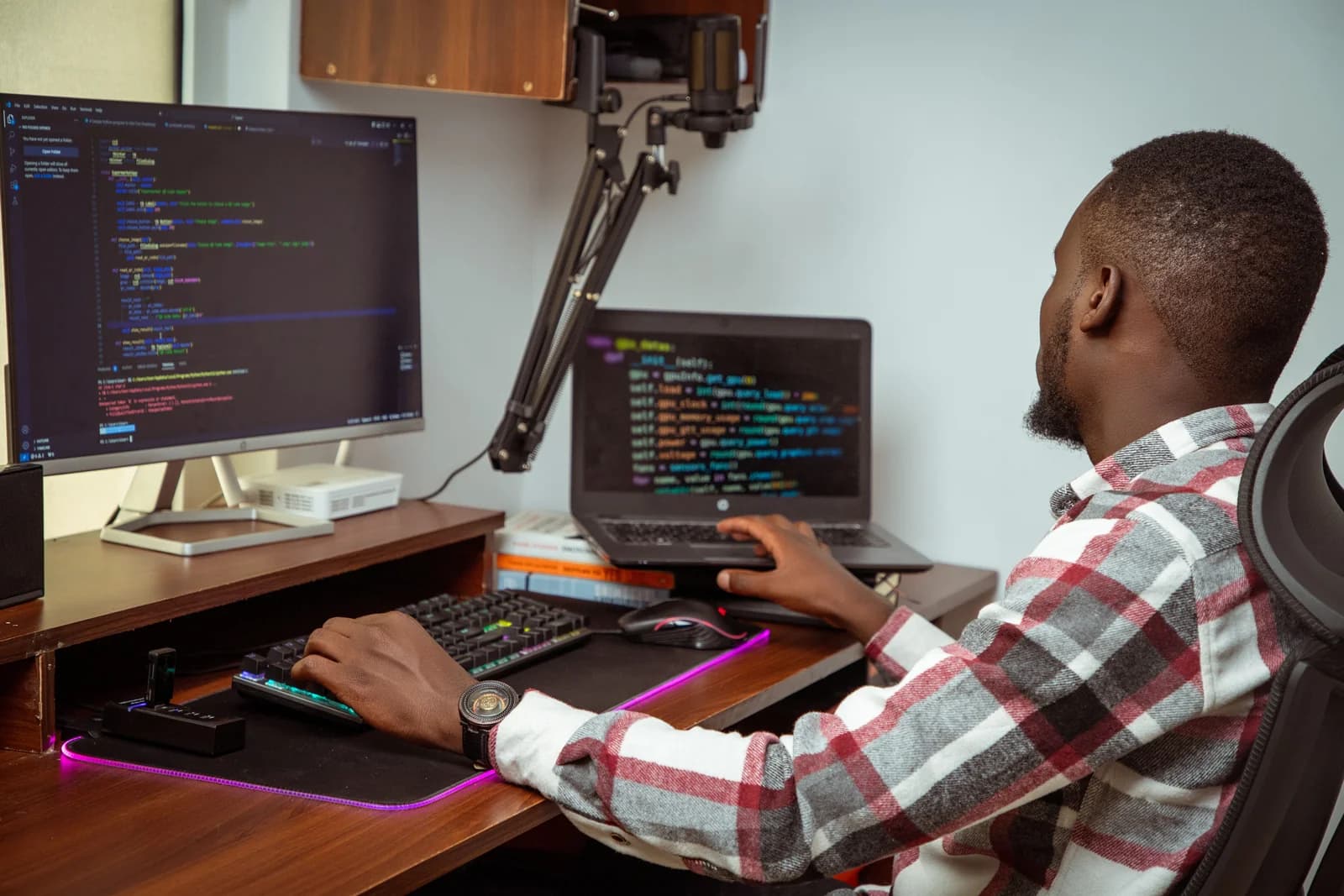 Developer writing code on a desktop monitor and a laptop at a desk